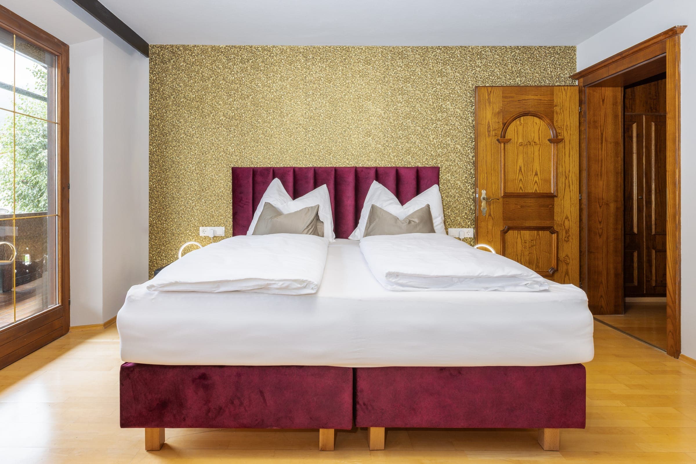 Schlafzimmer mit Doppelbett und bordeauxrotem Kopfteil